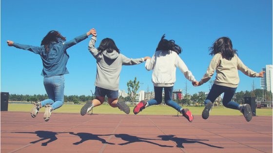 Group Of Homeschooled Girls Holding Hands Jumping In The Air